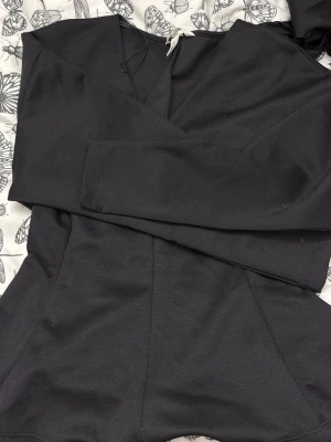 Svart hoodie med huva och dragsko - En tröja med klänning form i slutet har långa ärmar och en klassisk passform. Perfekt för en avslappnad look och enkel att matcha med andra plagg.