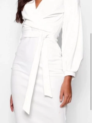 Vit omlottklänning med knytband - Stilren vit omlottklänning med v-ringning och långa ärmar. Klänningen har ett brett knytband i midjan som framhäver siluetten och ger en elegant look. Perfekt för dig som gillar minimalistisk och chic stil.