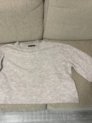Beige stickad tröja från 157 - Mysig beige stickad tröja från 157 med rund halsringning och avslappnad passform. Tröjan har ribbade muddar vid ärmslut och nederkant, perfekt för lager på lager och en enkel, clean look.