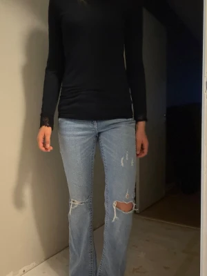 Ljusblå slitna raka jeans - Säljer ett par ljusblå jeans med raka ben och stora slitningar vid knäna. Jeansen har en klassisk femficksmodell och är tillverkade i denim. Perfekta för en avslappnad och trendig look.
