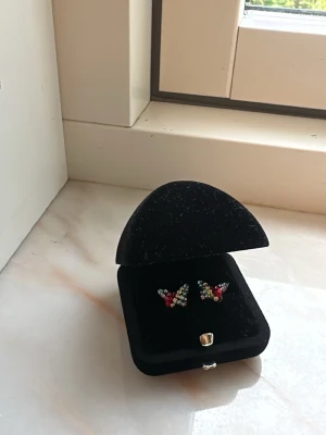 Fjärilsörhängen med färgglada pärlor - Unika örhängen med fjärilsdesign och glittrande stenar i flera färger. Från Hallbergs guld. Fint skick. Priset kan diskuteras. 