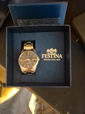 Festina herrklocka i silver - Snygg och stilren herrklocka från Festina med metallarmband i silverfärg och mörk urtavla. Klockan har klassisk design med tydliga markeringar och levereras i originalask. Perfekt accessoar för dig som vill ha en tidlös look. Kan inte frakta