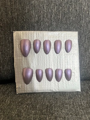 Press-on naglar || storlek L - Snygga press-on naglar i en metalliclila nyans med skimrande finish. Naglarna har en mandelformad design i storlek L. Perfekt för dig som vill ha ett trendigt och glansigt nagelset utan att behöva gå till salong.