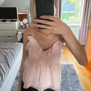 Ljusrosa volangig linnetopp - Supersöt ljusrosa linnetopp ifrån Nelly! Den passar perfekt som en fest topp men även om du bara vill klä upp dig lite extra. Storlek 32. Oanvänd. 