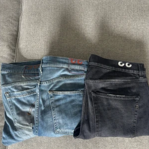 3 par Dondup jeans  - Säljer två par jeans, ett i klassisk ljusblå denim och ett i svart tvättad denim. Båda har raka ben, femficksmodell och tydliga sömmar. Snygga detaljer vid bakfickorna och tryck på linningen. Bulk pris 1299kr