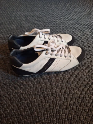 Tommy Hilfiger skor strl 44 - Tommy Hilfiger, sneakers i storlek 44. Vita med svarta och mörkgrå detaljer.