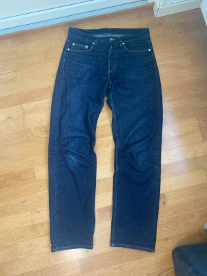 Mörkblå raka jeans från ARKET  -  Raka jeans från ARKET med svin snygga fades Storlek: W29 / L32Midjemått: 42 cm Benöppning: 20 cm Totallängd: 106 cm Skickar inom 24h
