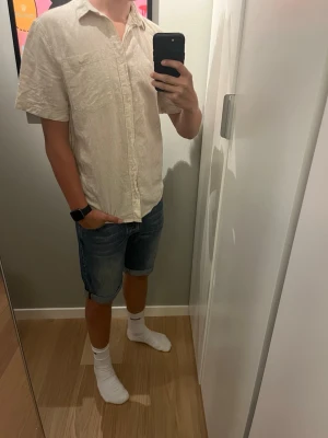 Beige linne piké  - En fräsch linne piké från H&M med en ficka på bröstet och en stilren krage perfekt för sommaren. Modellen är 179
