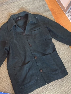 Overshirt  - Stilren svart overshirt från A Day's March med tre fickor framtill och stora knappar. Klassisk krage och rak passform. Tillverkad i ett tjockare tyg som ger en snygg struktur och passar perfekt som lager på lager-plagg. Ny pris 1499kr