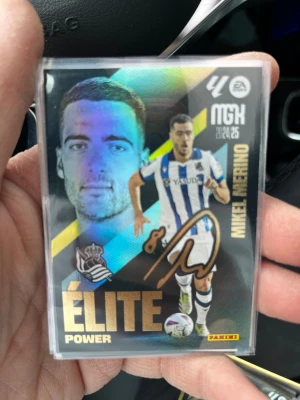 Panini fotbollskort Mikel Merino - Samlarobjekt: Panini fotbollskort med Mikel Merino från Real Sociedad. Kortet har en färgstark design med guldtext, spelarbild och autograftryck. Text på både fram- och baksida, samt statistik och klubbmärke. Perfekt för dig som gillar fotboll och samlarkort.