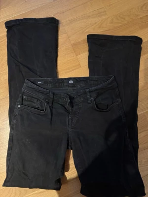 Svarta bootcut jeans från LTB - Svarta jeans från LTB i modellen Roxy med klassisk femficksdesign och bootcut-ben. Jeansen har normal midja och stängs med dragkedja och knapp. Perfekta för dig som gillar en tidlös och stilren look.