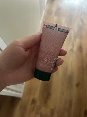 The Body Shop British Rose Shower Scrub - En duschskrubb från The Body Shop i doften British Rose. Tuben är rosa med ros-motiv och har en mörkgrön kork. Produkten är vegansk och ger en mjukgörande exfoliering för huden.