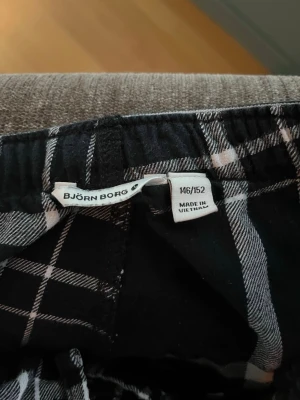 Svarta rutiga pyjamasbyxor Björn Borg - Säljer ett par svarta pyjamasbyxor från Björn Borg med vitt och grått rutmönster. Byxorna har resår i midjan och är tillverkade i ett mjukt tyg som passar perfekt för chillkvällar hemma.