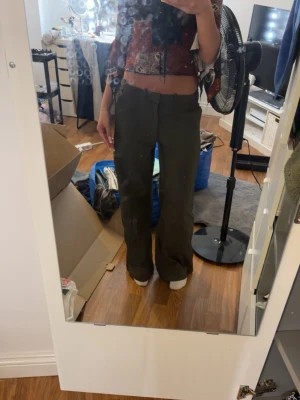 Mörkgröna vida kostymbyxor - Säljer ett par mörkgröna kostymbyxor med hög midja och raka, vida ben. Byxorna har bälteshällor och sidofickor för en clean look. Perfekta för dig som gillar en avslappnad men ändå stilren stil. Storlek M men passar mig som vanligtvis har S om man vill ha en luftigare look