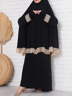 Svart långklänning med spetsdetaljer - Elegant svart långklänning med beige spetsdetaljer vid ärmslut och nederkant. Klänningen har lång ärm och en lös passform som ger en modest och stilren look. Perfekt för dig som gillar klassisk och tidlös stil.