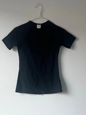 Svart tight badtröja soltröja  - Säljer en svart, åtsittande soltröja-tshirt med korta ärmar och rund hals. 