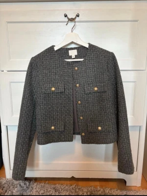 Kavaj från Zara  - Snygg grå kavaj från Zara  med fyra fickor framtill och dekorativa guldknappar. Kavajen har en rak, något kortare passform. Perfekt för dig som gillar en klassisk men trendig stil.