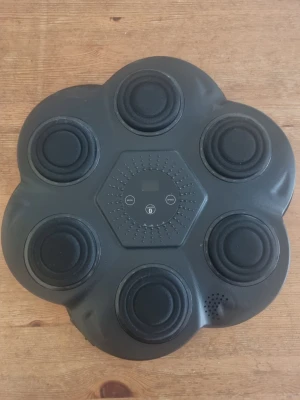 Svart elektronisk boxningsplatta - Elektronisk boxningsplatta i svart plast med sex runda punkter och digital kontrollpanel. Har knappar för mode, speed och bluetooth. Perfekt för träning hemma på ett roligare sätt! Behövs bara nya kardborrband för att sätta upp på väggen 