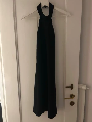 Backless halterneck klänning från BikBok - Backless halterneck klänning från BikBok med silver detaljer som sitter som ett kors på ryggen! Suppersnygg och går lite ovanför knäna på mig!