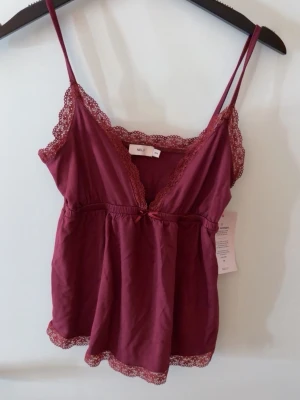 Nelly Linnne - Vinrött linne från Nelly med spets och en rosett i strl XXS. Oanvänd med lapp kvar. Super gulligt till sommaren 