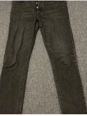 Svarta Levi's jeans med raka ben - Säljer ett par svarta Levi's jeans med raka ben och klassisk femficksdesign. Jeansen har knappgylf och detaljerade sömmar på bakfickorna. Tillverkade i slitstarkt denim som ger en tidlös look.