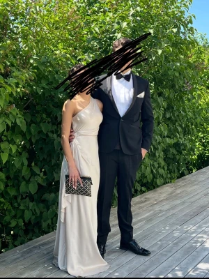 Champagnefärgad  balklänning - Elegant långklänning i champagnefärg med oneshoulder-design och mjukt fallande tyg. Klänningen har en detalj vid midjan och slits på sidan jag älskade det. Perfekt för balen. Jag är 155 och har sytt upp men den är som sagt mkt lång så funkar absolut för längre än mig. Dragkedja vid sidan