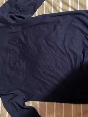 Mörkblå sweatshirt från USPA - Snygg mörkblå sweatshirt från USPA, väldigt ren använd kanske max 1 gång då den är för stor för mig. Storleken är M på tröjan men den är ganska flexibel, skulle kunna säga att den passar oxå S och L utan konstigheter. Priset jag frågar för är 150. Om du vill ha fler bilder så är det bara att hojta till!