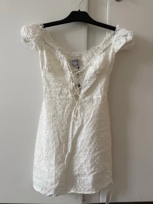 Vit klänning - Söt vit kortklänning i bomullstyg med puffärmar och snörning framtill samt broderade detaljer. Aldrig använd då den var för liten så i nyskick. Originalpåse och etiketter medföljer. Från WithJean och inköpt för 2400kr. Perfekt till studenten! 🎓