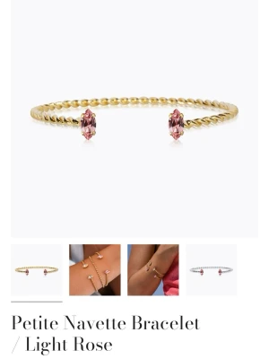 Guldarmband från Caroline Svedbom  - Snyggt armband i guldtonad metall med tvinnad design och två ljusrosa navetteformade kristaller i ändarna. Nytt skick!! Nypris är 600kr