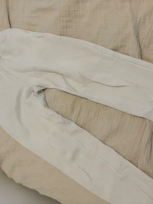 Vita mjukisbyxor med resår - Säljer ett par vita mjukisbyxor med resår i midjan och vid bensluten. Byxorna har en klassisk rak passform och är tillverkade i ett mjukt och bekvämt material, perfekt för chill dagar. Inga synliga loggor eller märken. Byxorna har använts väl och kom med egna bud och vid intresse
