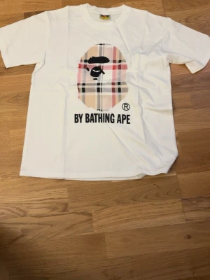 BAPE T-Shirt - Vit/Burberry/Beige BAPE Tröja. Storlek: S. Aldrig använt förut och den är helt ny. Startpriset är 300kr, DM vid intresse 🙏