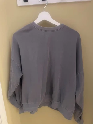 Oversized grå sweatshirt - Enkel oversized sweatshirt i en mjuk grå färg. Tröjan har rund halsringning, långa ärmar och ribbade muddar vid ärmslut och nederkant. Perfekt för en avslappnad och stilren look.