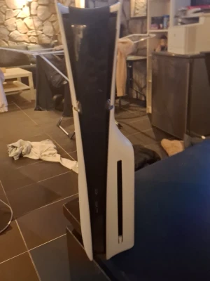 PlayStation 5 konsol med skivläsare - PlayStation 5 konsol från Sony med futuristisk design i vitt och svart. Konsolen har en vertikal form och är tillverkad i plast. Utrustad med skivläsare för fysiska spel och media. Perfekt för gaming och streaming plus ett ps5 