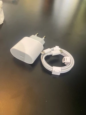 USB-C laddare med kabel - Säljer en vit USB-C väggadapter tillsammans med en matchande USB-C till Lightning-kabel. Perfekt för snabbladdning av din iPhone eller iPad. Båda delarna är i stilren design och tillverkade i tålig plast. Passar till de flesta Apple-produkter med USB-C och Lightning.