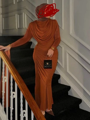 Lång  klänning med drapering - Från HOUSE OF CB NYPRIS 1199 Säljer en elegant långklänning i varm brun ton med draperad överdel och figurnära passform. Klänningen har långa ärmar och ett svepande tyg som ger en exklusiv look. Perfekt för dig som vill sticka ut på nästa event. 