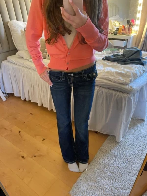 Mörkblå bootcut jeans  - Säljer ett par mörkblå bootcut jeans med vita kontrastsömmar och låg midja.