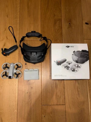 DJI - Säljer ett DJI NEO FPV-dronekit med grå drönare, svart FPV-headset, grå handkontroll, batteriladdare och tre batterier. Allt är original från DJI och perfekt för dig som vill testa FPV-flygning. Smidig design och lätt att ta med sig har även Dji care. Kartong medföljer.