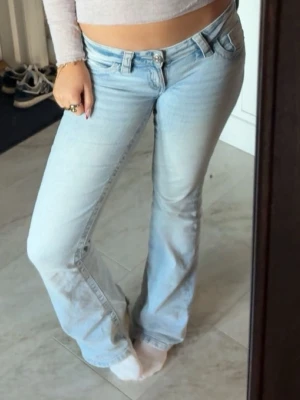 Ljusblå bootcut jeans - Säljer ett par ljusblå bootcut jeans med klassisk femficksdesign och normalhög midja. Jeansen har en snygg tvättad look och är tillverkade i ett mjukt denimtyg som sitter bekvämt. Perfekta för en avslappnad och trendig stil. Ifrån Gina tricot 14+🙏
