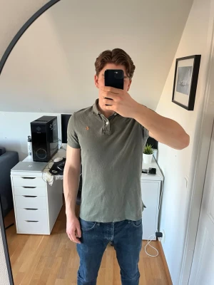 Grön pikétröja från Morris - Snygg grön pikétröja från Morris med klassisk krage och två knappar framtill. Tröjan har en liten broderad logga på bröstet och är tillverkad i bomull. Det är små fläckar på bröstet (se bild 5). Hör gärna av dig vid frågor!