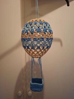 Virkad luftballong  - Virkad luftballong Virkad luftballong med en liten korg. Banden är inte knutna för hårt så det går att reglera längden till korgen om man önskar.  Virkad i bomullsgarn och stärkt med lim. Se sista bild som referens för hur man kan göra, här har vi satt in en uppladdningsbar lampa från rusta.  Korgen är 6.5 cm bred och 5 cm hög Ballongens omkrets är 55 cm 