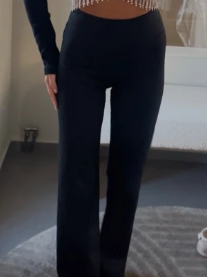 Svarta utsvängda leggings - Säljer ett par svarta leggings med utsvängda ben och hög midja. De är stretchiga och sitter tight upptill för en snygg siluett. Perfekta att styla med crop tops eller oversized tröjor.