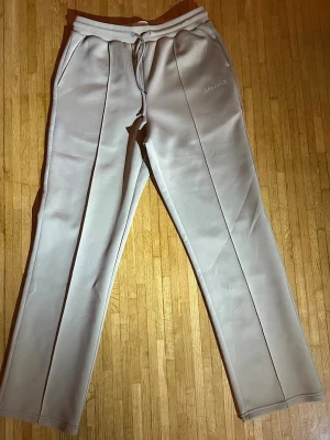 Beige mjukisbyxor från Les Deux - Les Deux byxor helt nya (produktionsfel) Säljer ett par stilrena byxor från Les Deux i ljus/beige ton. Byxorna är aldrig använda, men säljs till reducerat pris på grund av ett produktionsfel. Tyget är lätt uttänjt vid midjan (se bild). Felet påverkar inte användningen eller komforten, men syns vid närmare granskning, därför är priset satt därefter. Byxorna har i övrigt en snygg passform och bekväm kvalitet med lätt stretch. Nypris: 1099 kr Pris: 299 kr Ett stilrent plagg till mer än halva priset