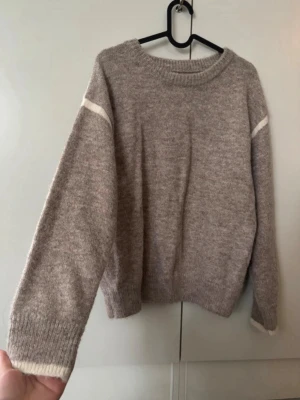 Beige tröja med vita detaljer, storlek S - Beige stickad tröja med vita detaljer. Mycket fint skick, sticks inte! Lite boxy modell, perfekt inför hösten. Använd en gång så i nyskick☺️