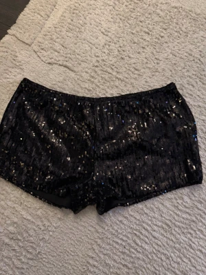 Svarta paljettshorts - Glittriga svarta shorts, lågmidjade strl S. men står storlek L då det är asiatiskt storlek. Passar inte mig så säljer vidare 