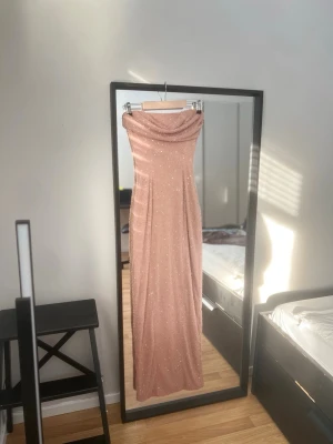 Oh Polly glittrig strapless maxiklänning UK 8  - Axelbandslös långklänning från Oh Polly i glittrigt meshmaterial med draperad överdel och figurnära passform. Helfodrad med dragkedja baktill samt slits bak för rörelse. Den är även stretchig.  Storlek UK 8 / US 4.  Använd en gång. I gott skick.  Passar exempelvis till fest, bröllop eller bal.