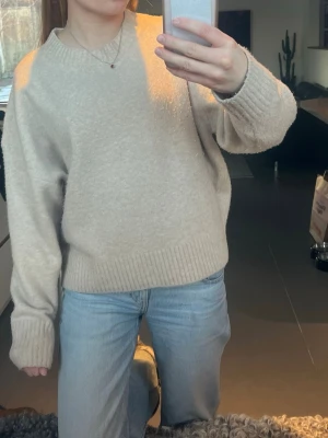 Beige oversized stickad tröja - Mysig beige stickad tröja med avslappnad passform och breda ribbade muddar vid ärmslut och nederkant. Väldigt fint skick och utöver det bra kvalitet!! 