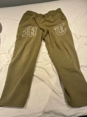 Tuttolente byxor  - Olivgröna mjukisbyxor från Tuttolente med vita tryckta bokstäver på framsidan. Byxorna har resår i midjan och mjukt fleecefoder på insidan. Perfekta för chill dagar och streetwear-stil. Passar även storlek M. 