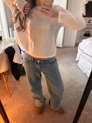 Vit långärmad rodebjer topp - Säljer en vit croppad topp med långa ärmar och rak passform. Toppen har en enkel, clean look och är gjord i ett tunt och mjukt material som känns skönt mot huden. Perfekt för dig som gillar minimalistisk stil.