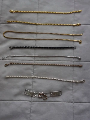 Mix av tunna armband i guld och silver - Säljer ett set med åtta tunna armband i olika stilar och färger. Några är guldfärgade, andra silverfärgade och ett är svart. Materialen varierar mellan metall och kedjor, och ett armband har en unik bricka med gravyr och kedjedetalj. Perfekt för att mixa och matcha till din outfit. Kontakta mig för pris på specifikt armband! 