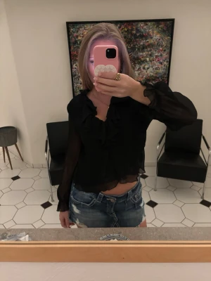 Svart volangblus - Snygg svart blus med volangdetaljer framtill och v-ringning. Är lite genomskinlig 💕